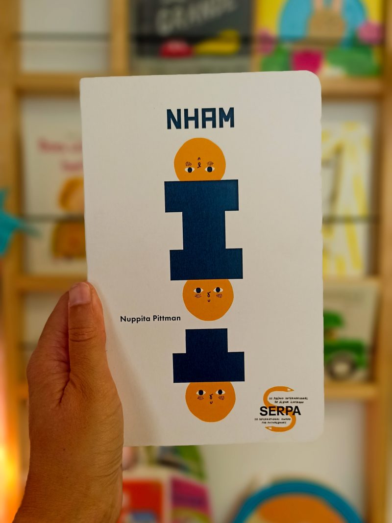 "Nham" é um livro cartonado, de cantos arredondados, convidativo à exploração, que conta a história de três personagens e da sua aventura.