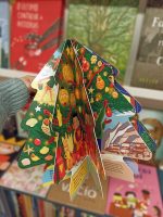 Numa celebração global do Natal, este livro carrossel em formato de árvore em folhas duras pode ser aberto e montado para criar uma árvore de Natal que se segura sozinha usando um íman magnético integrado.